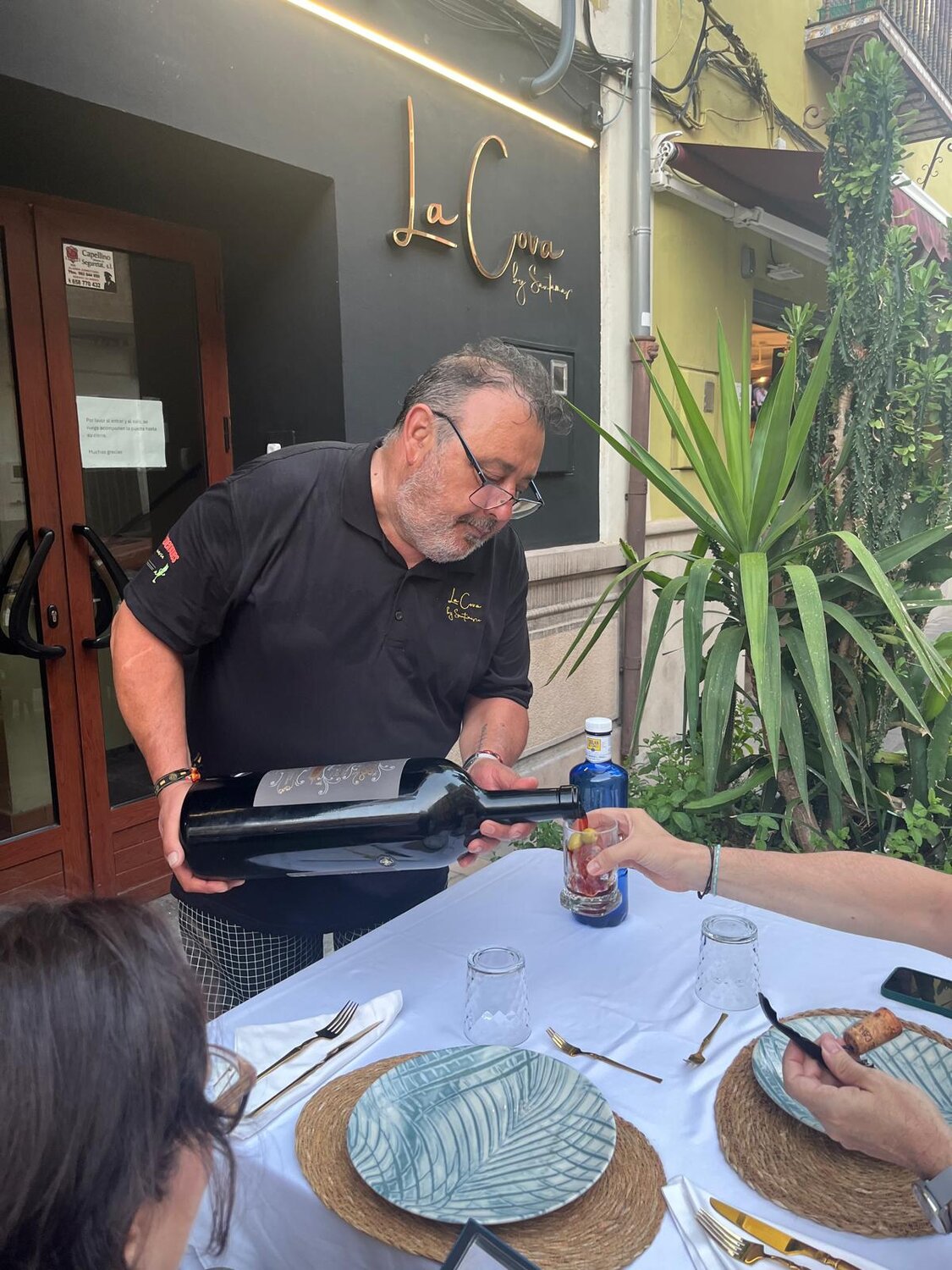 Atención en mesa sirviendo vino en la terraza de La Cova