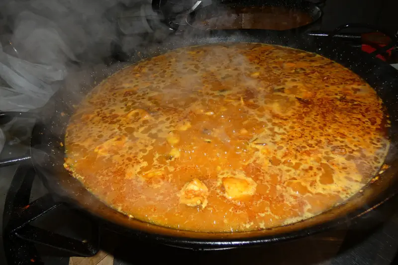 Paella cocinándose al fuego en La Cova